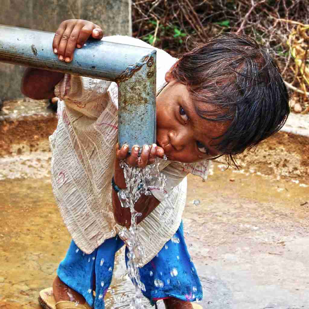 Child drinking clean water from a Jesus Well