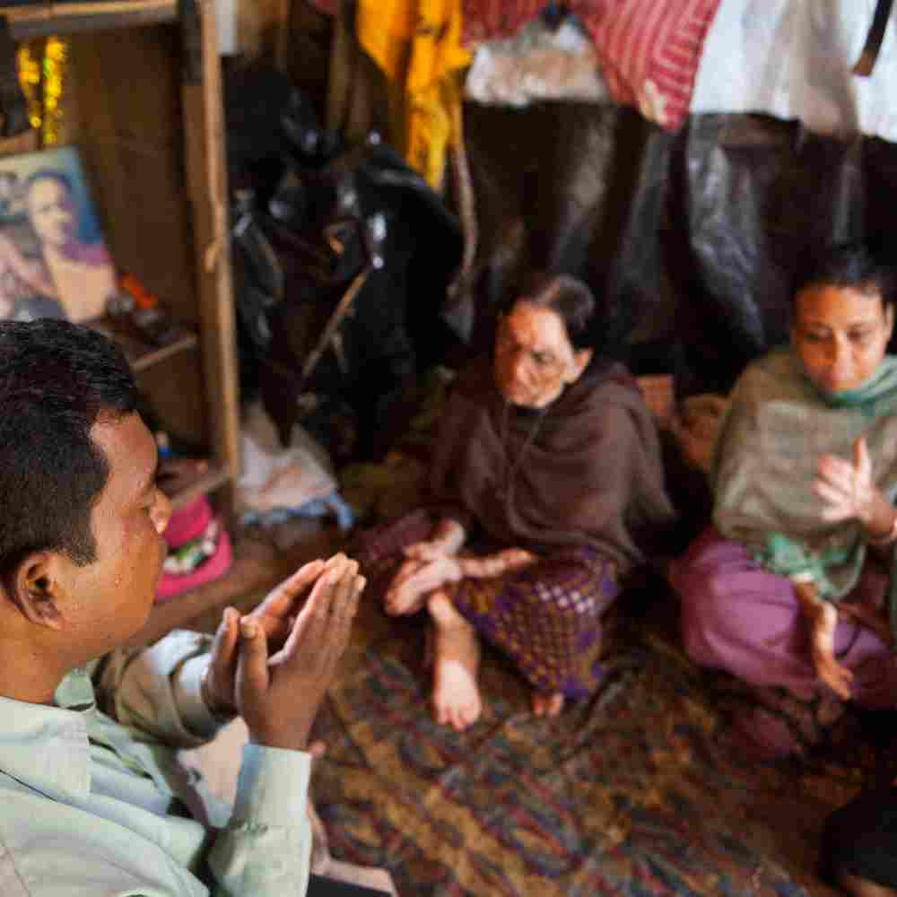 National missionary worker praying for a family in poverty living in the slums