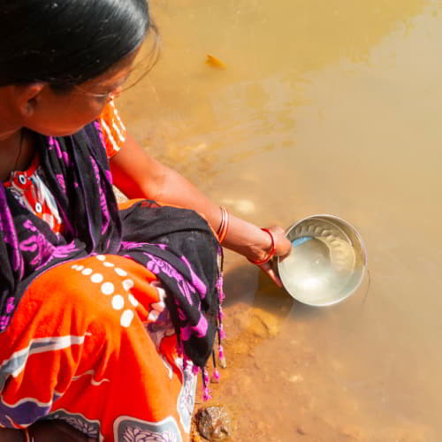South Asian woman in poverty collects unsafe water