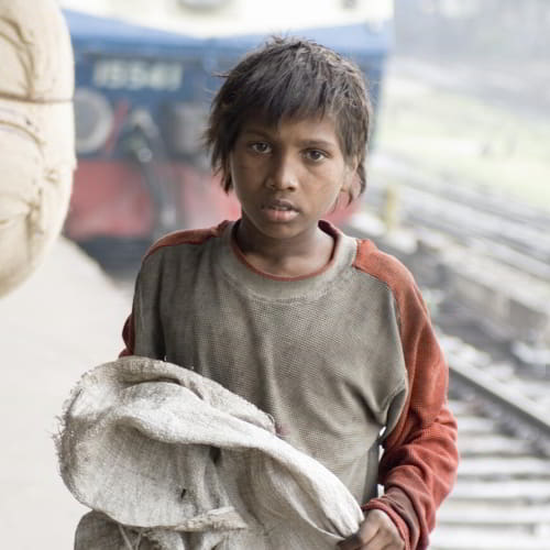 Child in poverty collecting garbage in the streets of South Asia