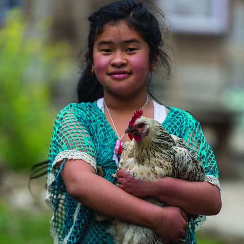 A girl holding an income-generating gift of farm animal through GFA World
