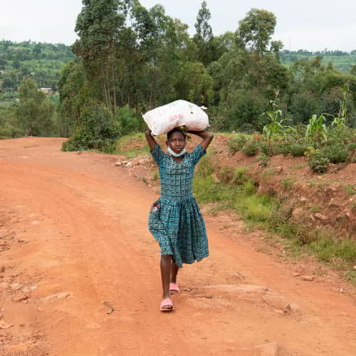 Young girl in poverty from Rwanda, Africa walking from a day of labor