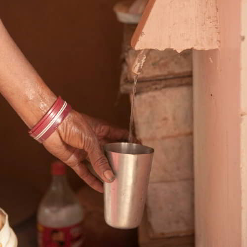 Woman fills a cup with clean drinking water through GFA World Jesus Wells