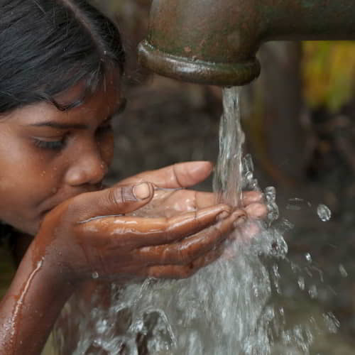 Young girl drinks water through Jesus Wells, a clean water initiative by GFA World