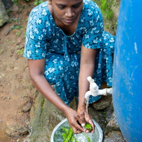 Woman washes vegetables using clean water from GFA World Jesus Wells