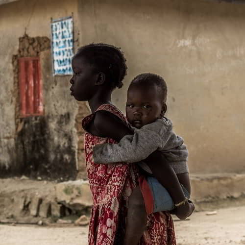 Young girl in poverty carrying a baby