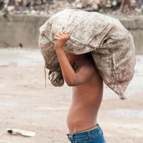 Boy in child labor collecting trash