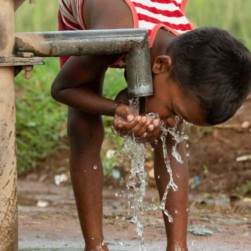 Young child drinks clean water through GFA World water solutions, Jesus Wells