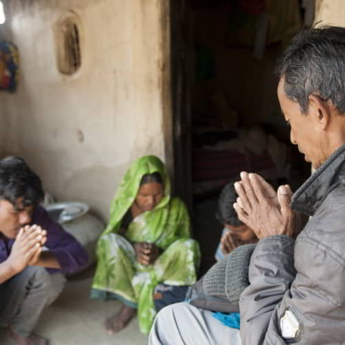 GFA World national missionary praying for a family in poverty