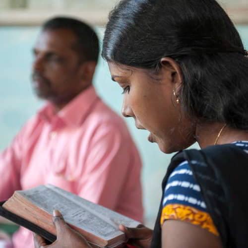 GFA World woman missionary reads her Bible out loud for her blind husband who is also a national missionary