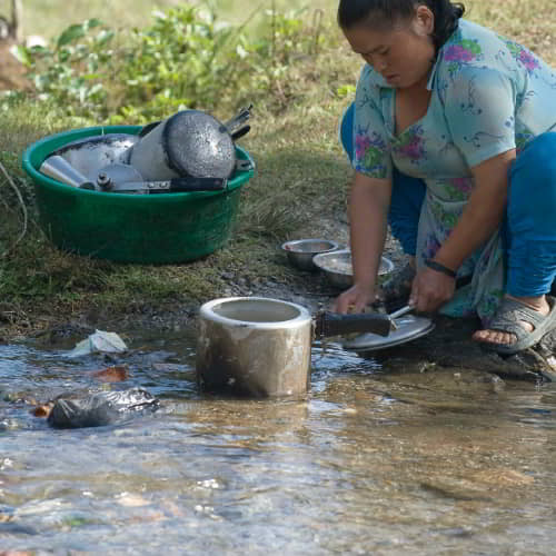 Woman using impure water to wash pots