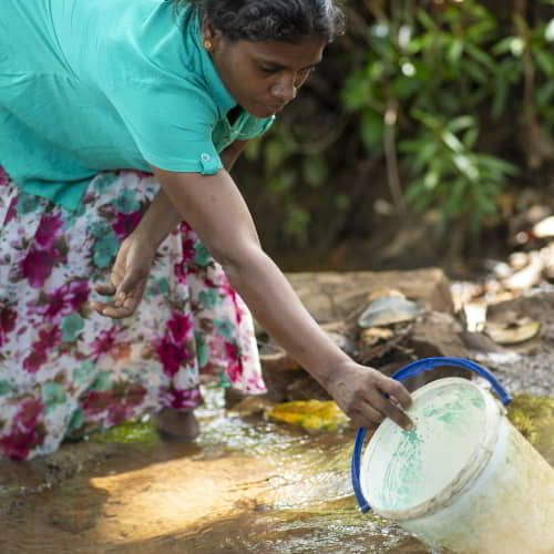 South Asian woman in poverty collects unsafe water
