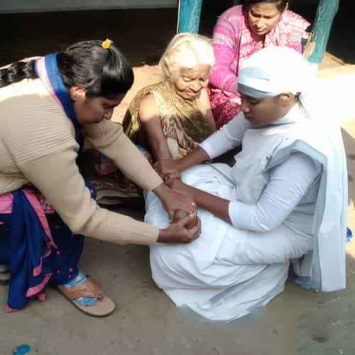 GFA World female missionary workers massaging an elderly woman's arm