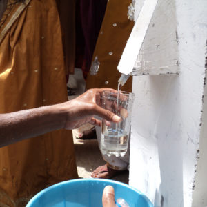 Glass being filled with clean water through BioSand water filter