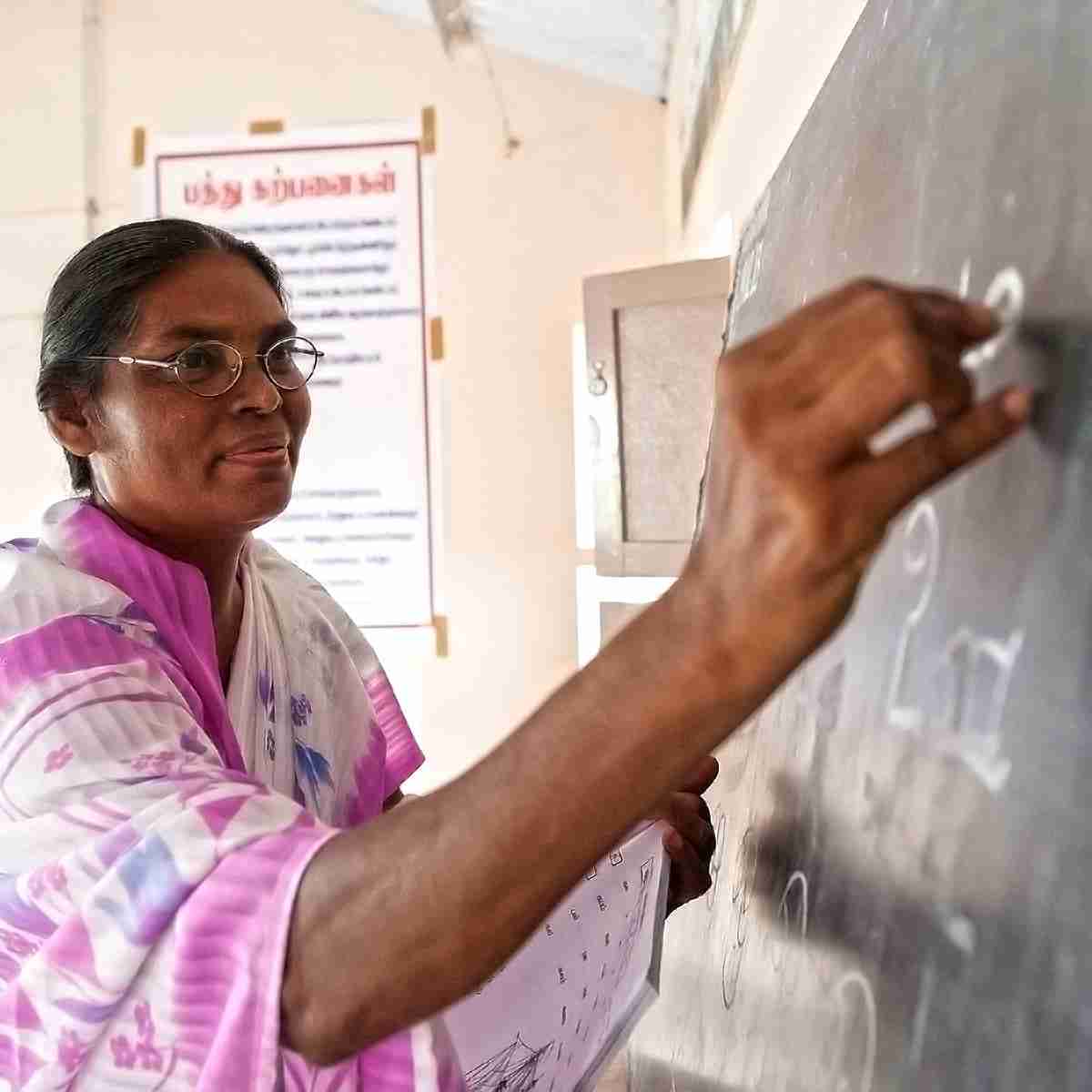 Women national worker teaches Literacy Class using chalkboard