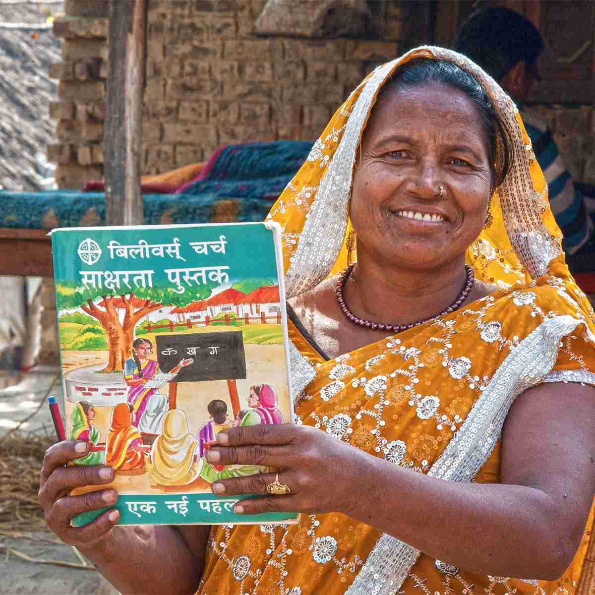 Woman holding up the free literacy book she received from adult women's literacy class