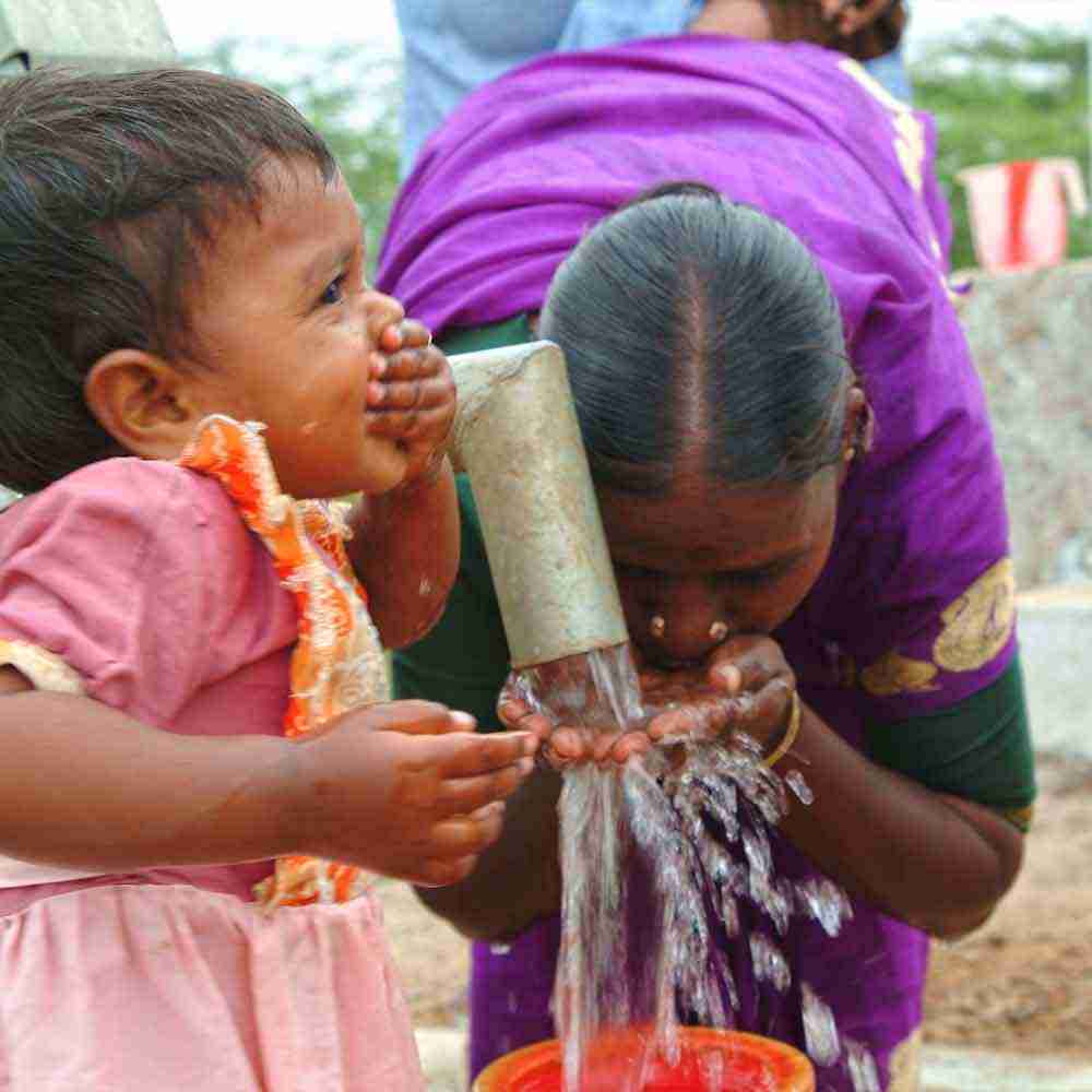 Woman and little girl drinking clean water from Jesus Well