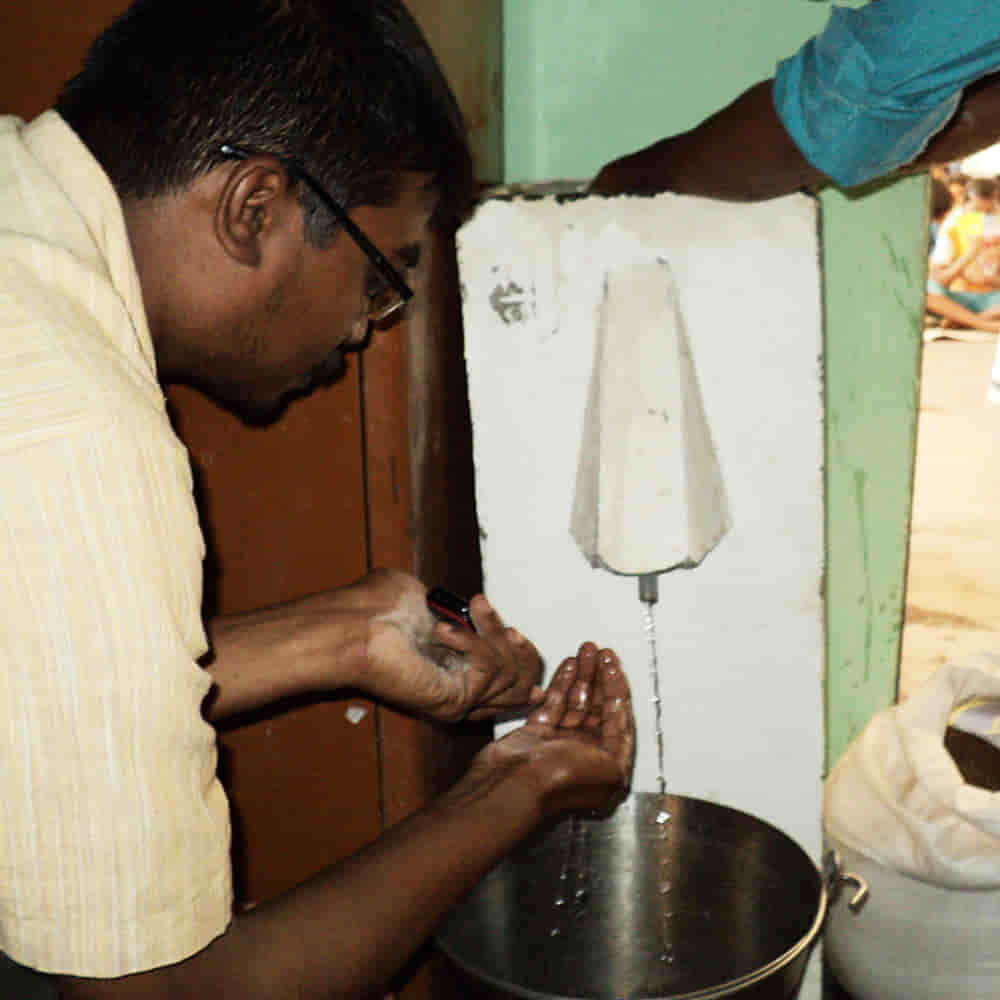 Man checks the clean water filtered through BioSand water filters