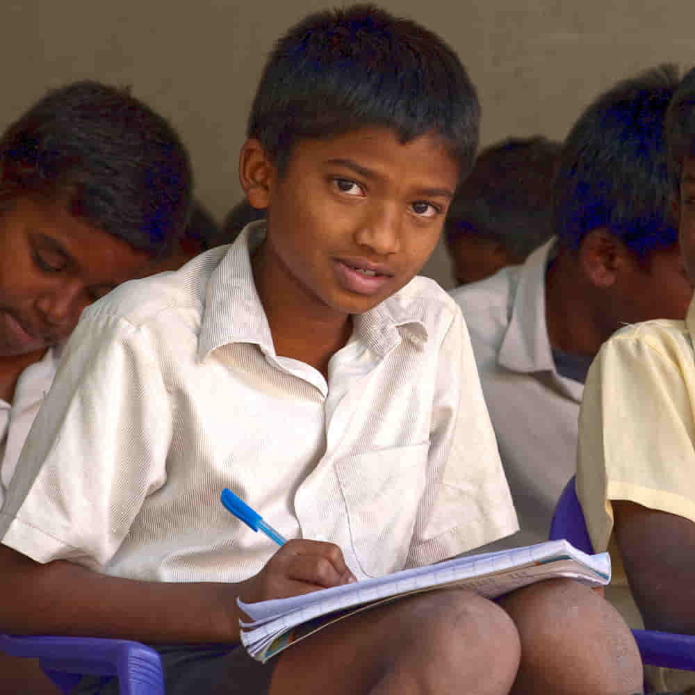 Boy child writing in GFA World child sponsorship Bridge of Hope class