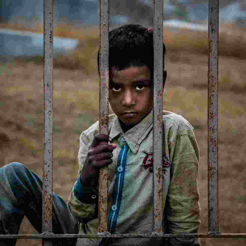 Distressed and sad child behind bars