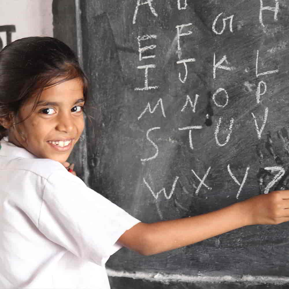 Girl writing the alphabet on a classroom chalkboard
