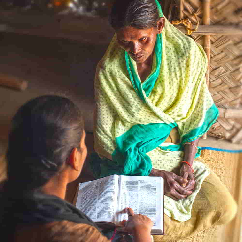 Woman missionary teaching literacy using her Bible