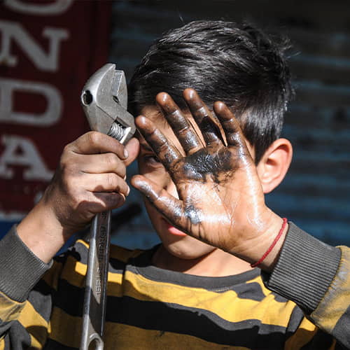 A child labor victim working in a car repair shop