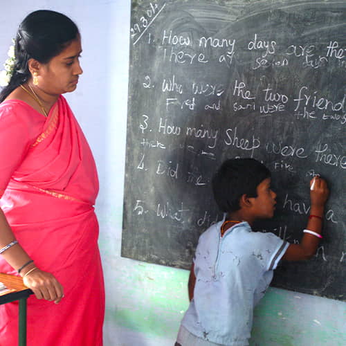 Girl writing on chalkboard in GFA World child sponsorship program