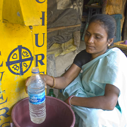 Woman collects clean water through GFA World BioSand Water filter