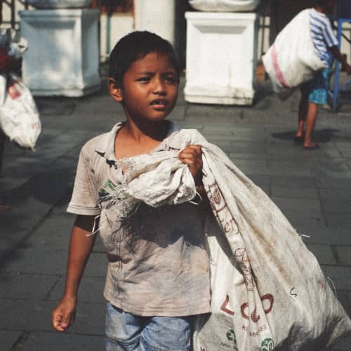 Boy in child labor collecting trash