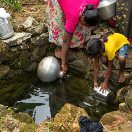 Mother and child drawing unclean water from an open water source