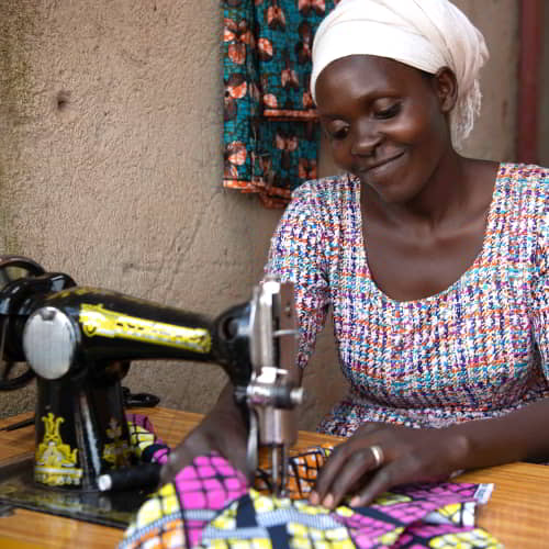 A woman being trained how to sew with a sewing machine