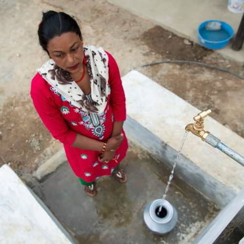 Woman collects clean water through GFA World Jesus Wells